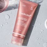 Pink tube of Medicube Collagen Night Wrapping Mask on a gray background with water droplets.